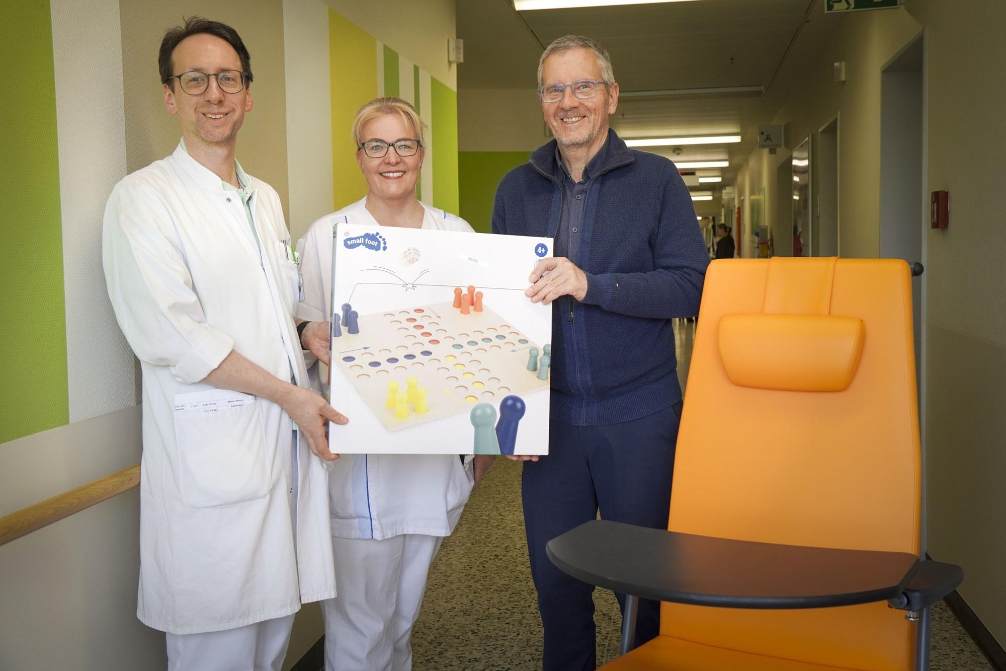 Chefarzt Dr. Stefan Dörr, Vereinsvorsitzender Dr. Norbert Thiele und Pflegefachleitung Anja von Zogorski mit Mobilitätsstuhl und Gesellschaftsspiel für die Geriatrie