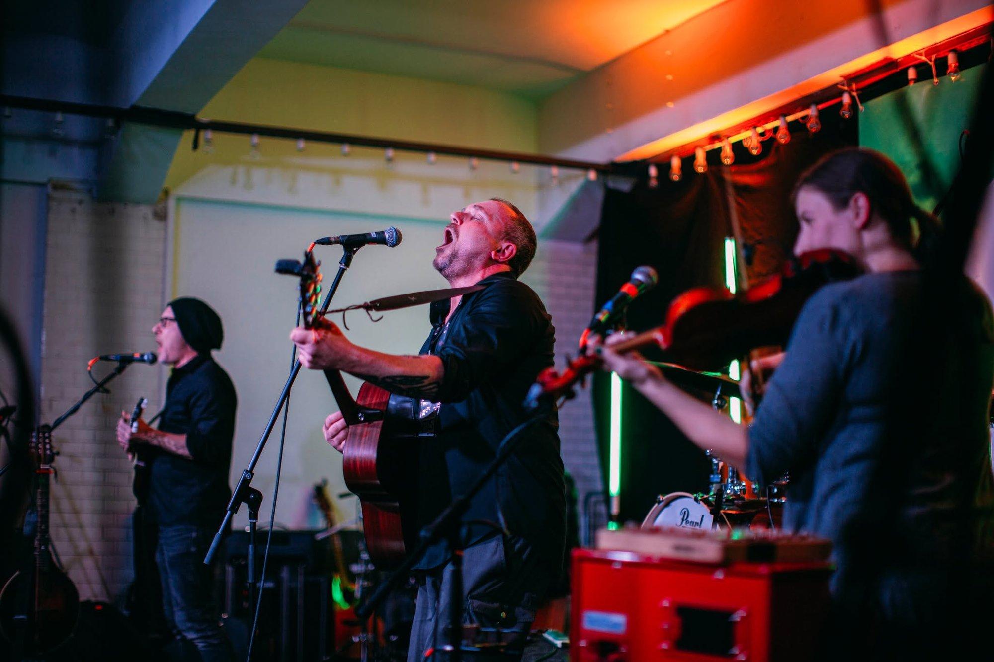 Band mit Sänger tritt unter magentafarbenem Bühnenlicht beim Kultursommer auf