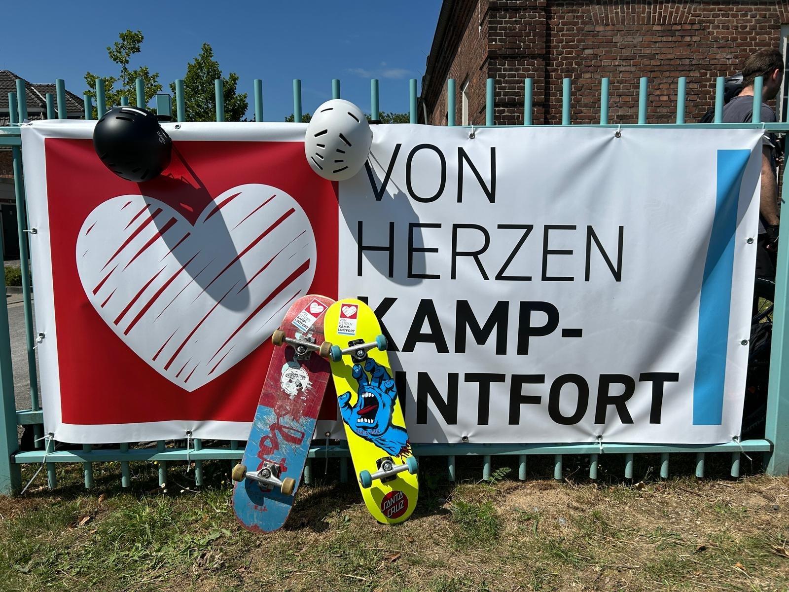 Skateboards und Helme lehnen am Von-Herzen-Kamp-Lintfort-Banner
