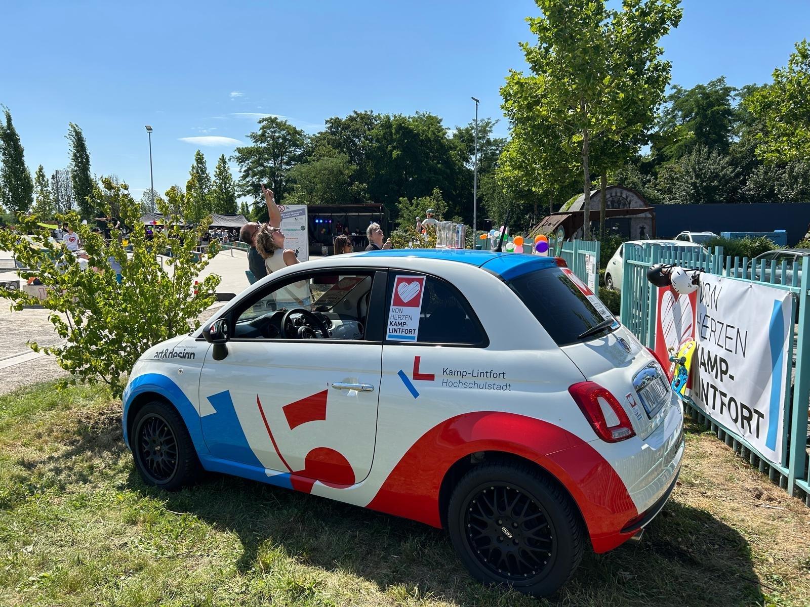 Der gebrandete Von-Herzen-Fiat 500 (Kamp-Lintfort Hochschulstadt) am Rand des Festivalgeländes