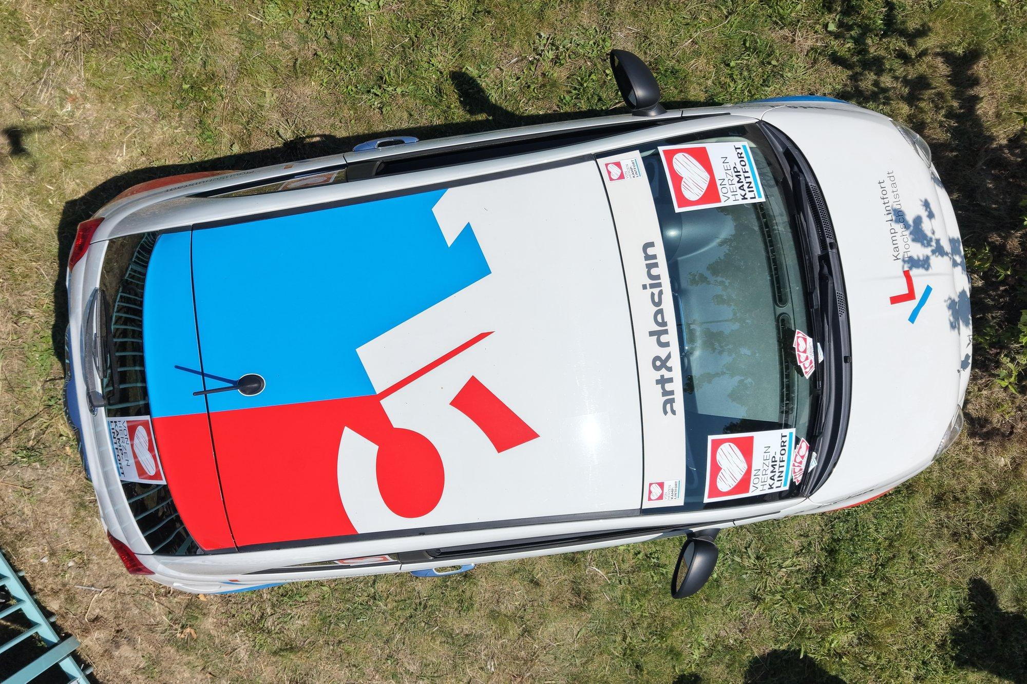 Luftaufnahme des gebrandeten Von-Herzen-Fiat 500 mit dem 5-Logo auf dem Dach