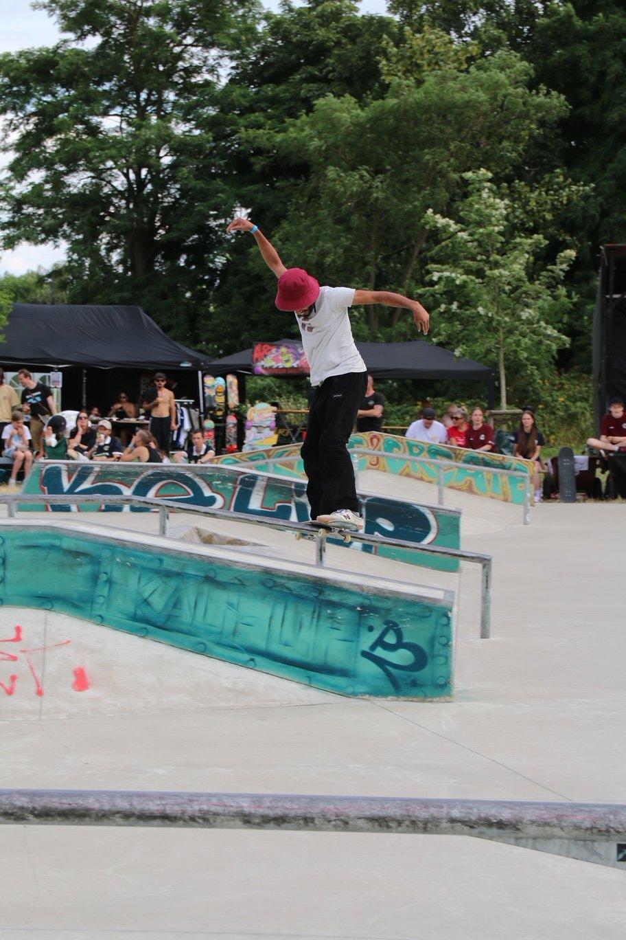 Skater grindet auf dem Rand der bunt bemalten Bowl im Skatepark am Schirrhof