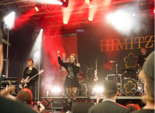 Die Band HIMITZU auf der rot ausgeleuchteten Bühne, Sängerin und Bassistin vor dem Publikum