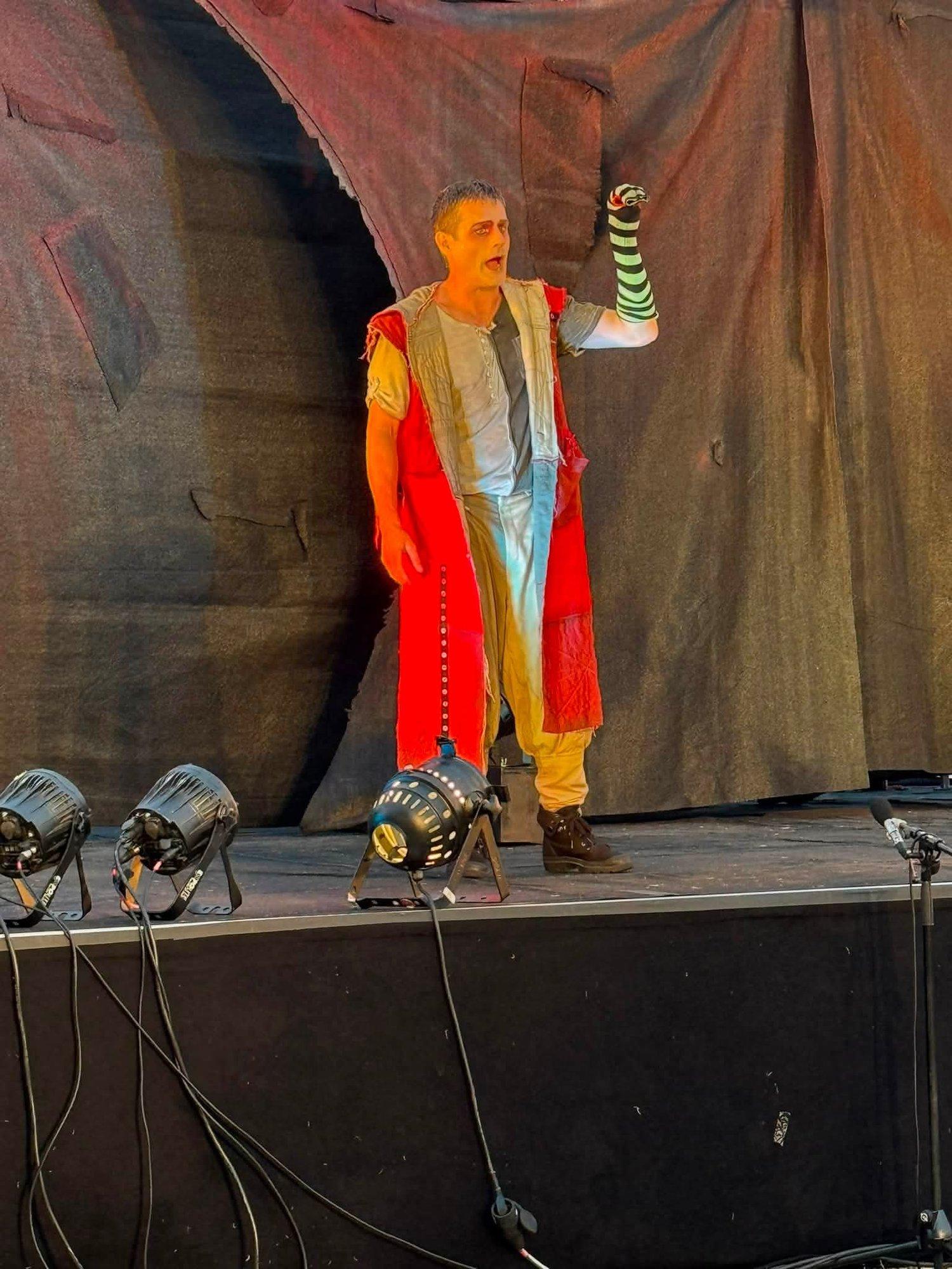 Schauspieler in bunter Kostümierung hält einen ringelbestrumpften Fuß in die Höhe