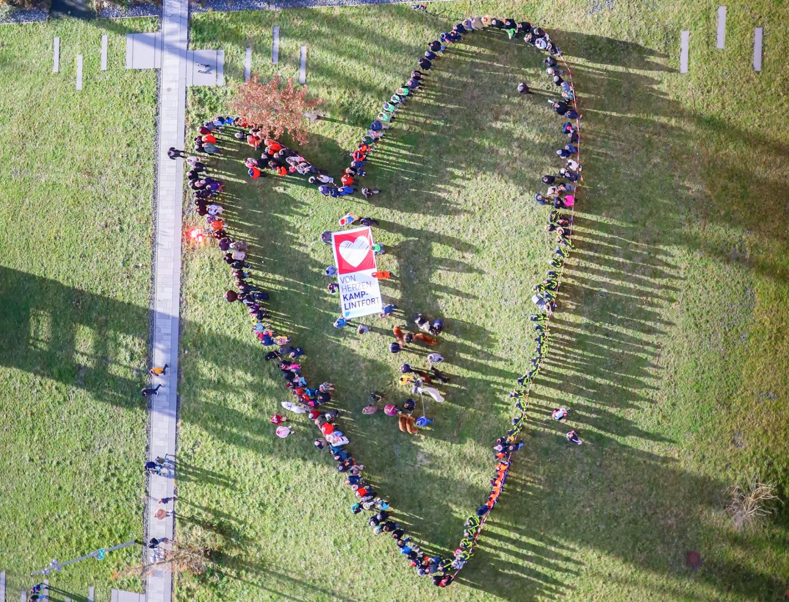 Eine Gruppe von Menschen, die gemeinsam ein großes Herz im Zechenpark bilden