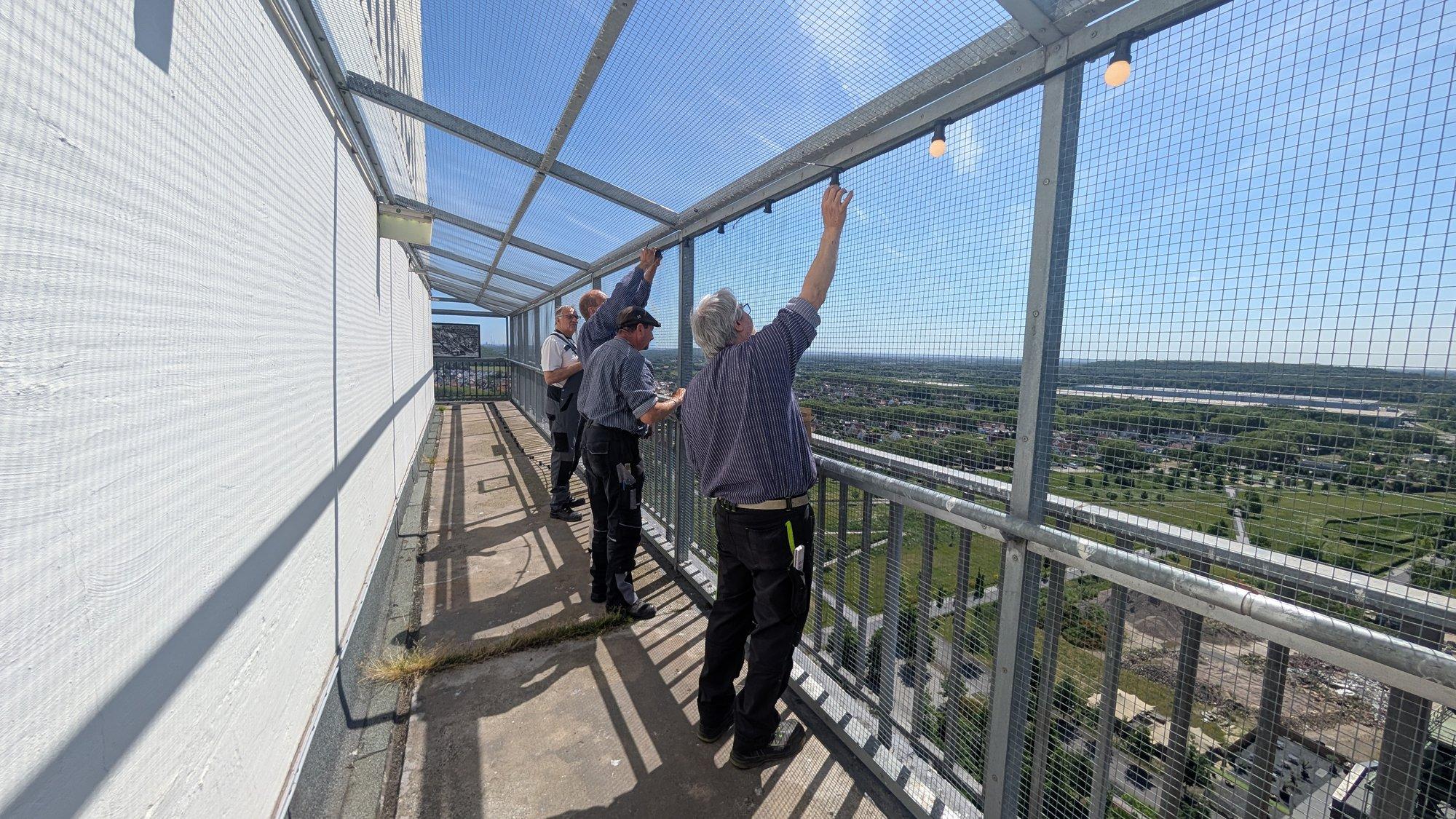 Mitglied der Fördergemeinschaft bringt auf der Balustrade des Zechenturms die neue Lichterkette an