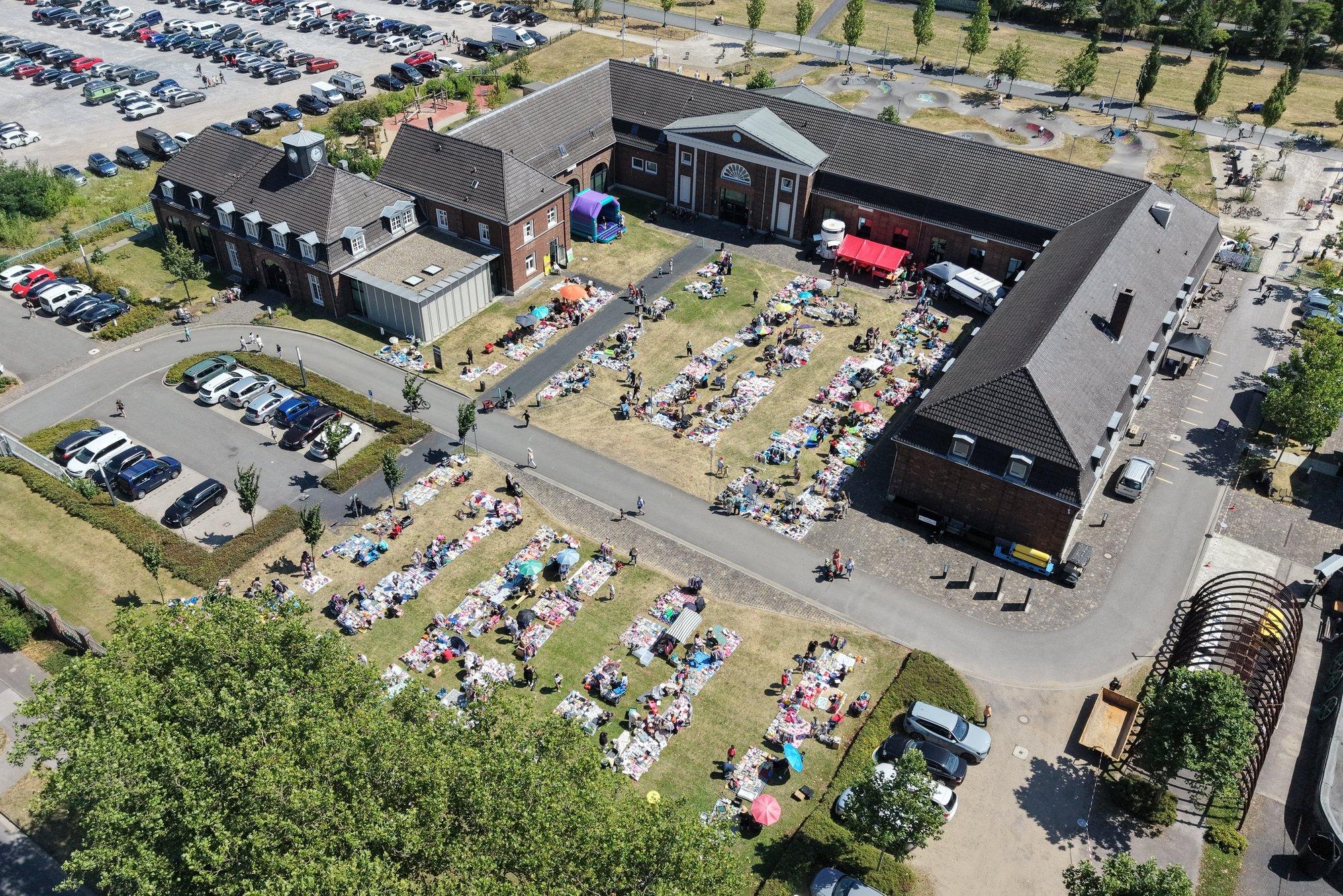 Luftaufnahme des Schirrhofs in Kamp-Lintfort mit dem Kindertrödelmarkt auf der Wiese beim Auftakt des Kultursommers 2026