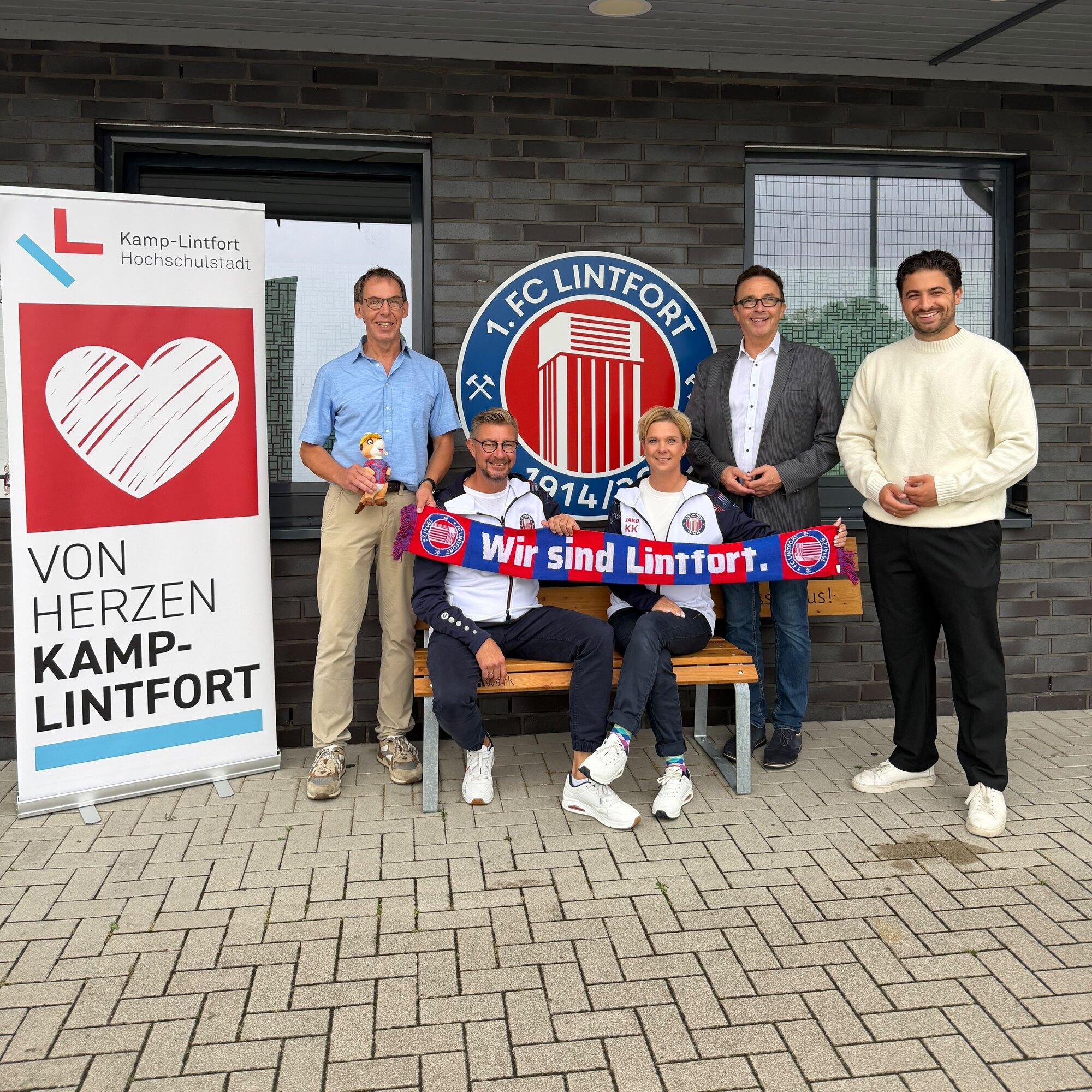 Übergabe der Mitgliedschaft auf der Sportanlage des 1. FC Lintfort vor dem Vereinswappen, daneben das Roll-up von Von Herzen Kamp-Lintfort